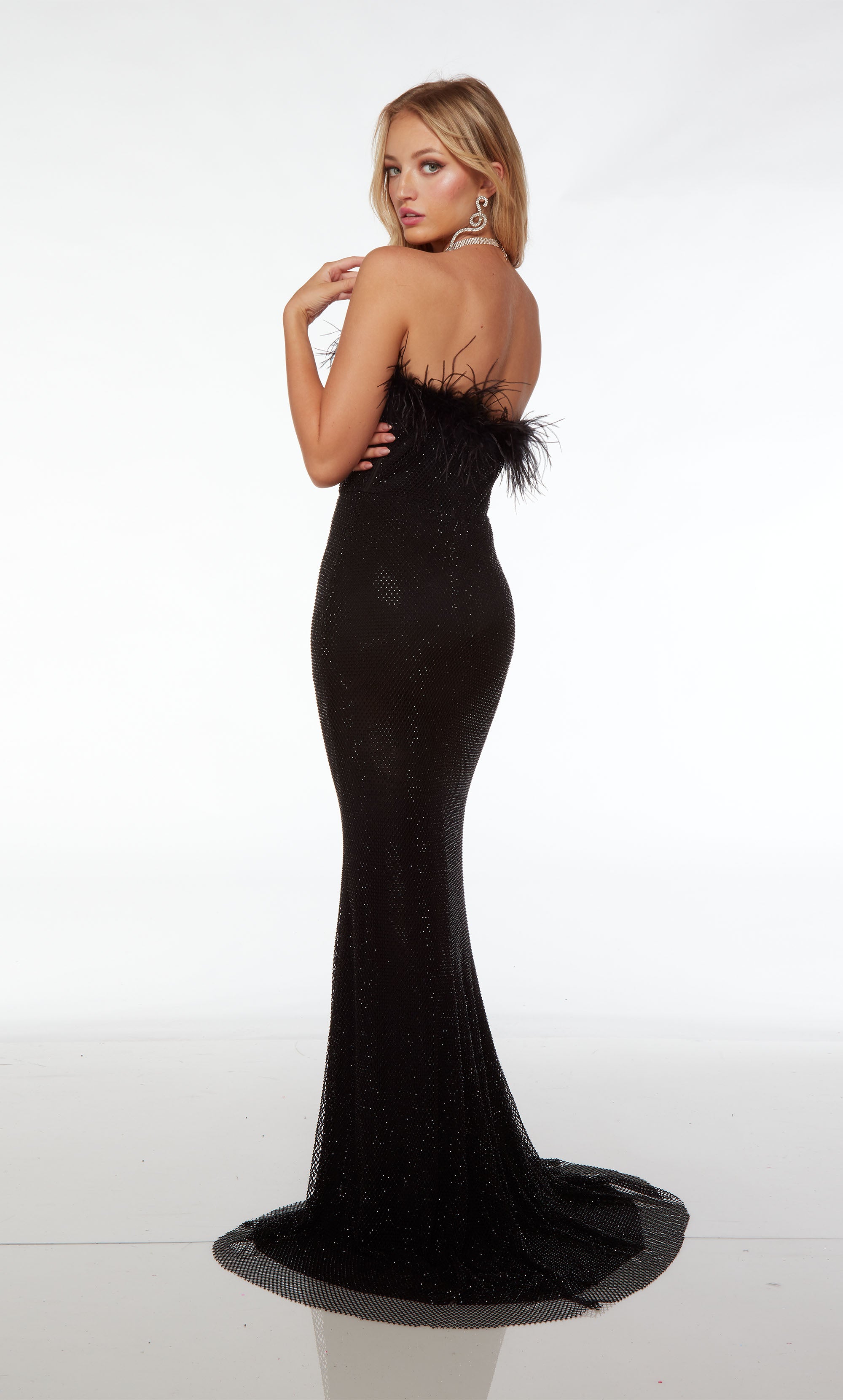 Fitted black hotfix gown featuring an strapless feather-trimmed neckline, corset bodice, zipper enclosure, and an graceful train.