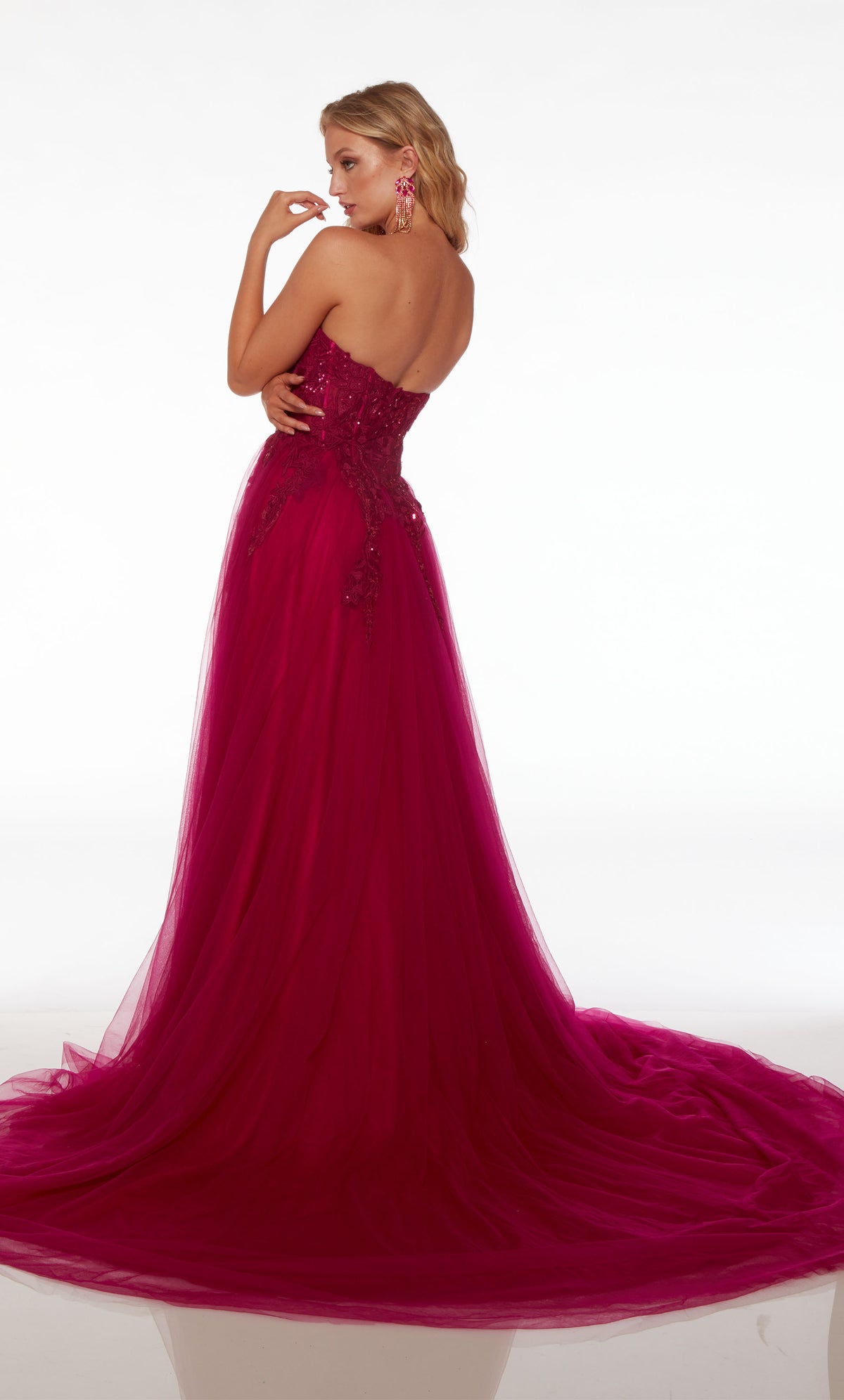 Strapless pink formal dress with lace bodice, tulle skirt featuring an side slit, zipper back enclosure, and an gracefully long train.