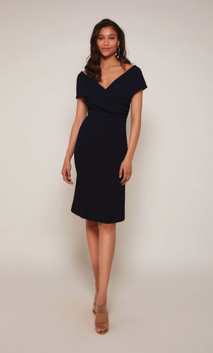 A chic, knee length cocktail dress with an off the shoulder neckline, ruching detail, and a closed zipper back in midnight blue.