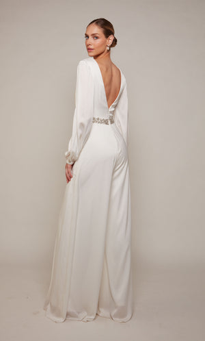 A long sleeve, open back jumpsuit with an jeweled waist and wide leg pant in ivory.