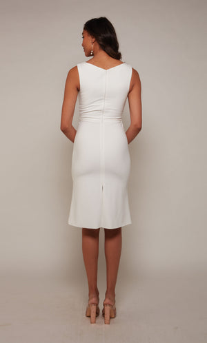 A sleeveless, ivory cocktail dress with a closed zipper back. The skirt is fitted with a knee length hemline.