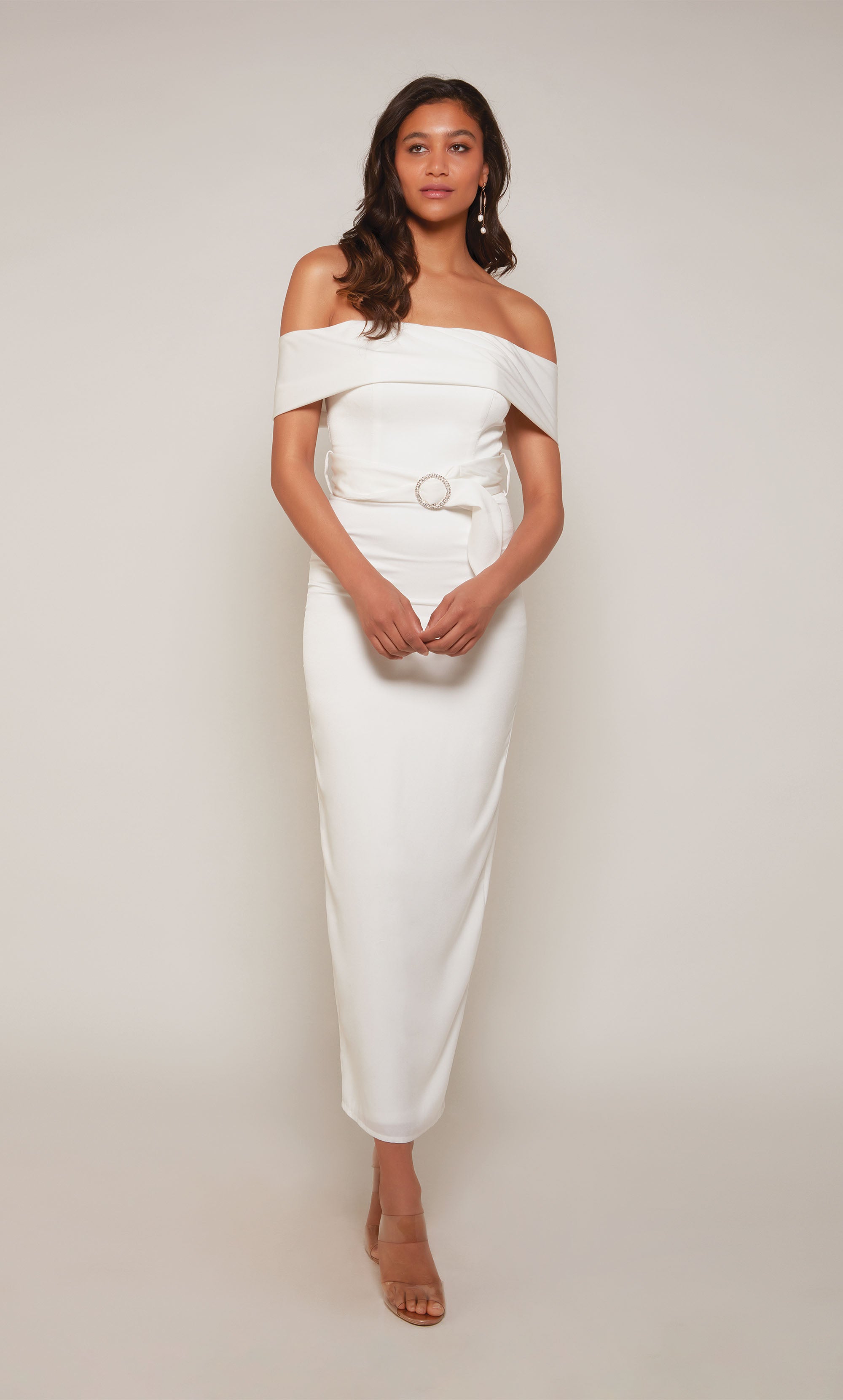 A  white, satin midi dress with an off the shoulder neckline and thick belt at the waistline. The skirt is a fitted pencil skirt with a back slit.