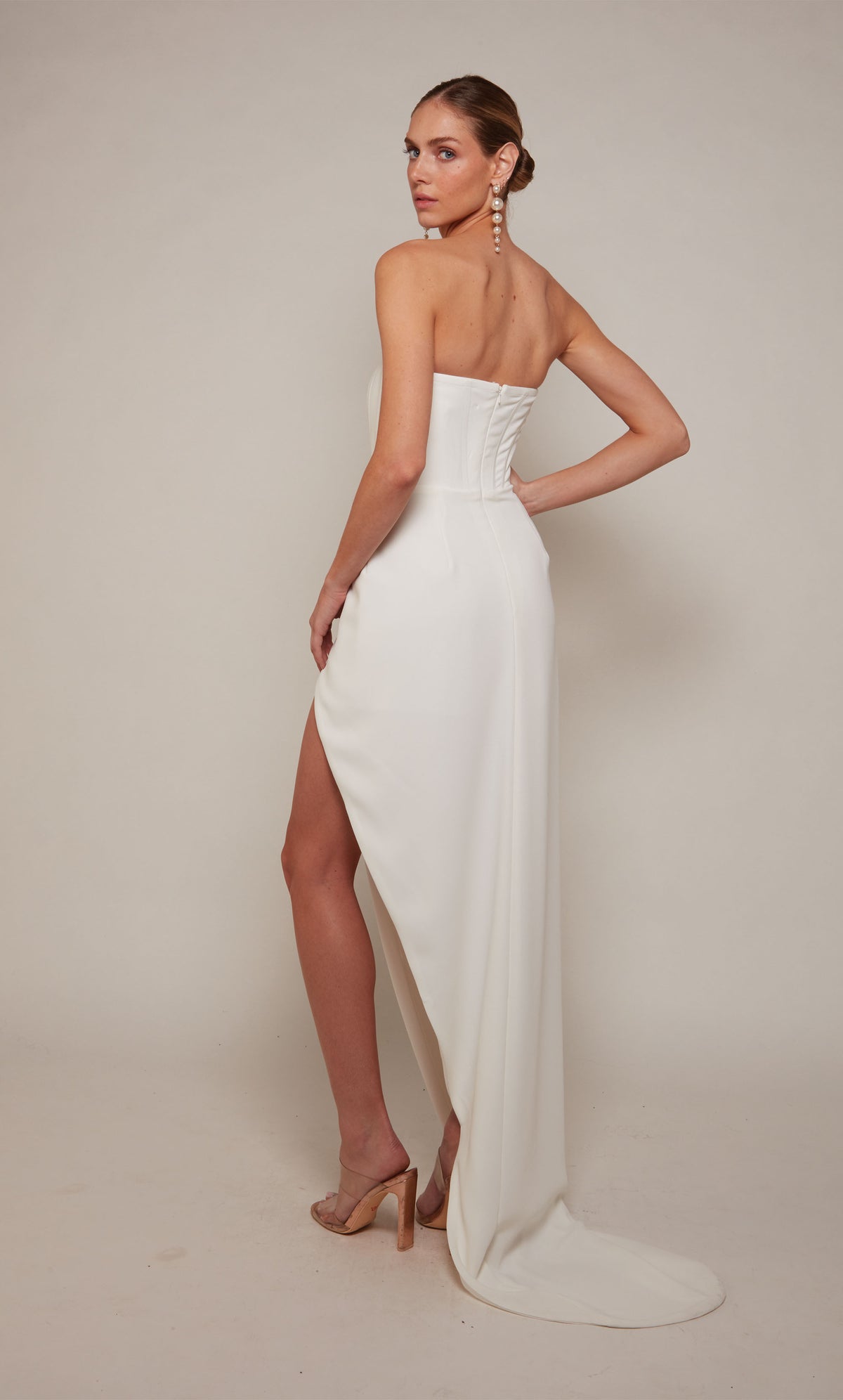 A modern corset wedding dress with a high-low hemline, zip-up back, and slight train in ivory