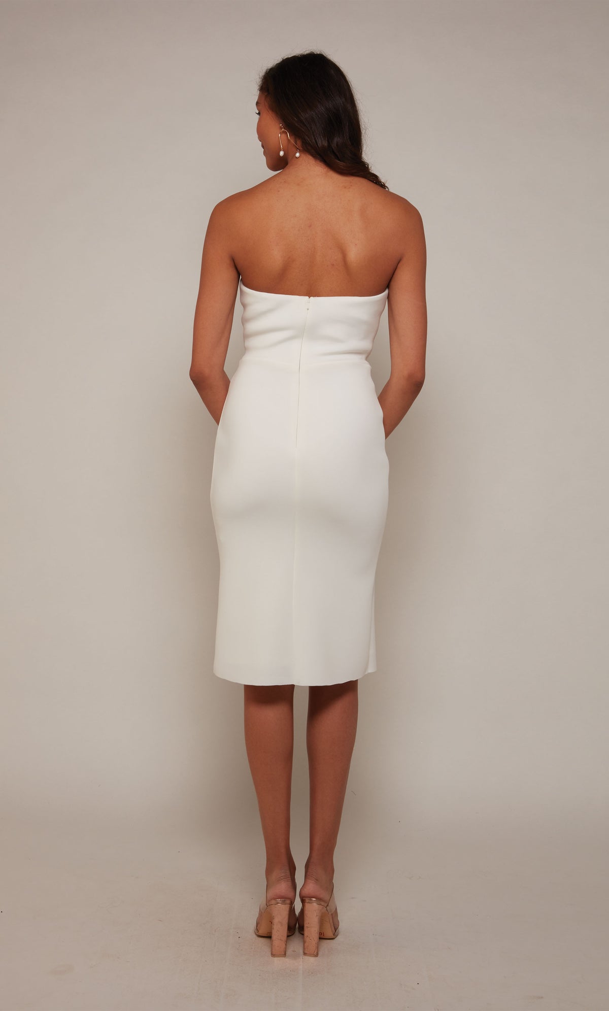 A knee length, white cocktail dress with a strapless sweetheart neckline and a zipper closure at the back.