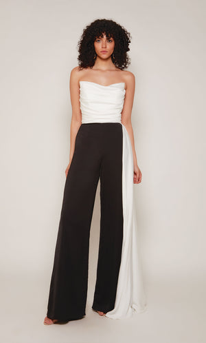 A chic, strapless jumpsuit with a white ruched top and cascading drape, and black wide leg pant.