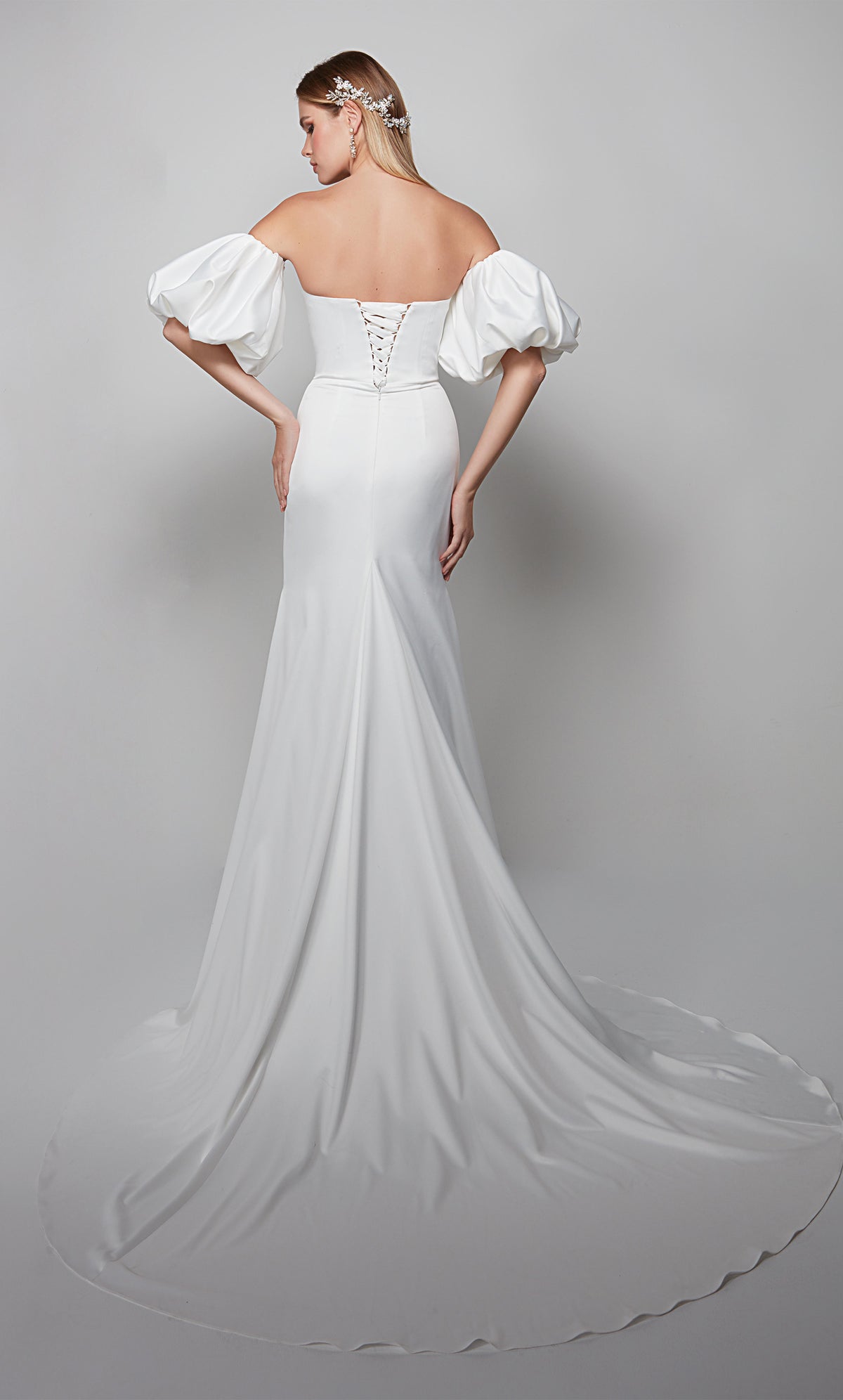 White satin wedding gown with a lace up back, removable puff sleeves, and train.