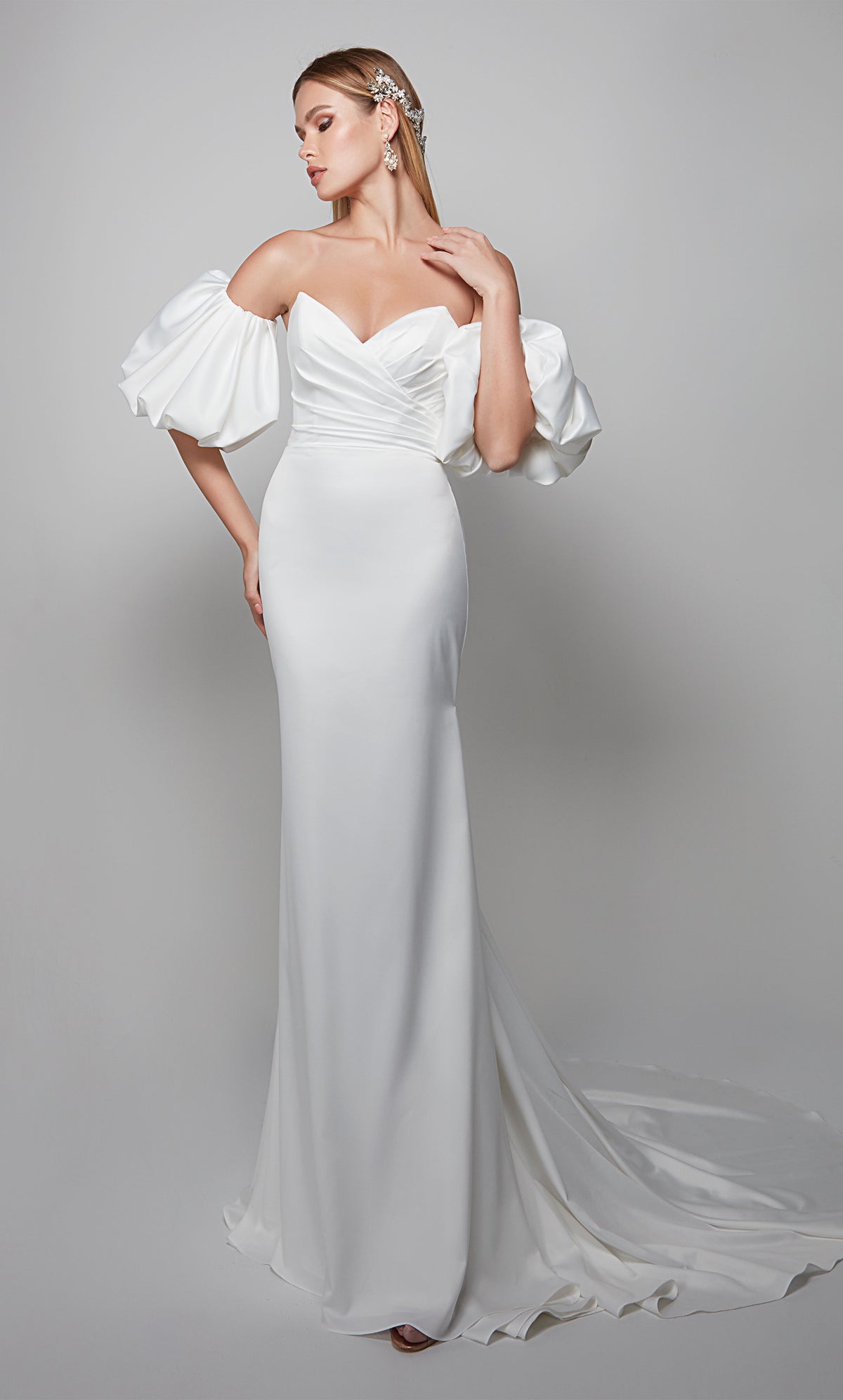 Simple strapless wedding dress with pleated bodice, detachable puff sleeves, and train in white satin.