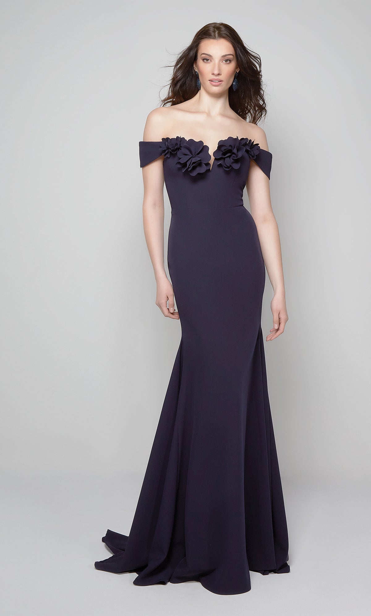 Midnight blue fit and flare formal gown featuring an off the shoulder bodice enhanced with a beautiful flower volant. Color-SWATCH_7062__MIDNIGHT