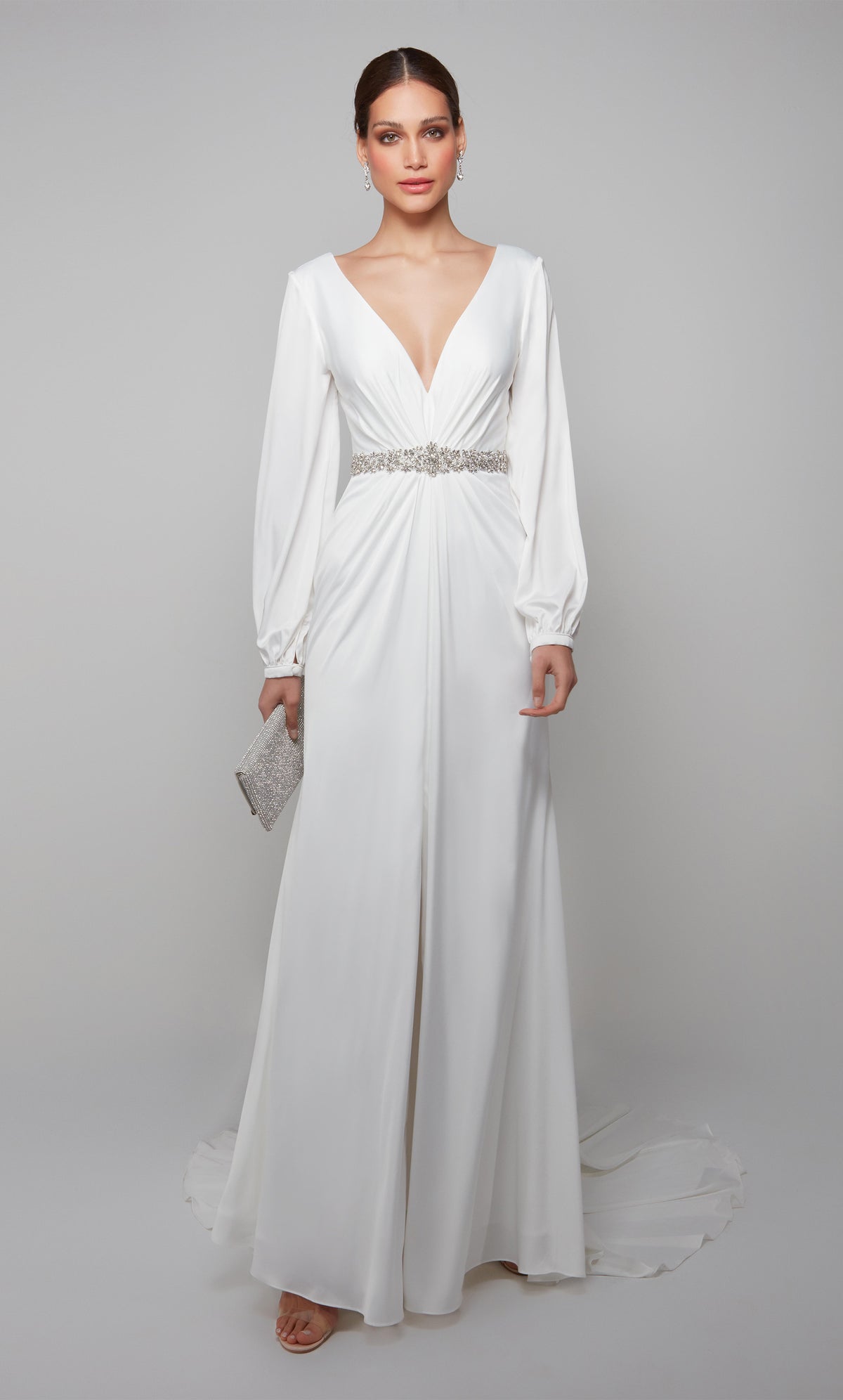 Long sleeve draped wedding dress with a plunging neckline, faux belt, and front slit in white.