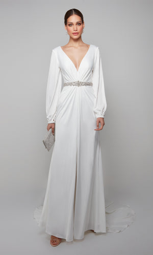 Long sleeve draped wedding dress with a plunging neckline, faux belt, and front slit in white.