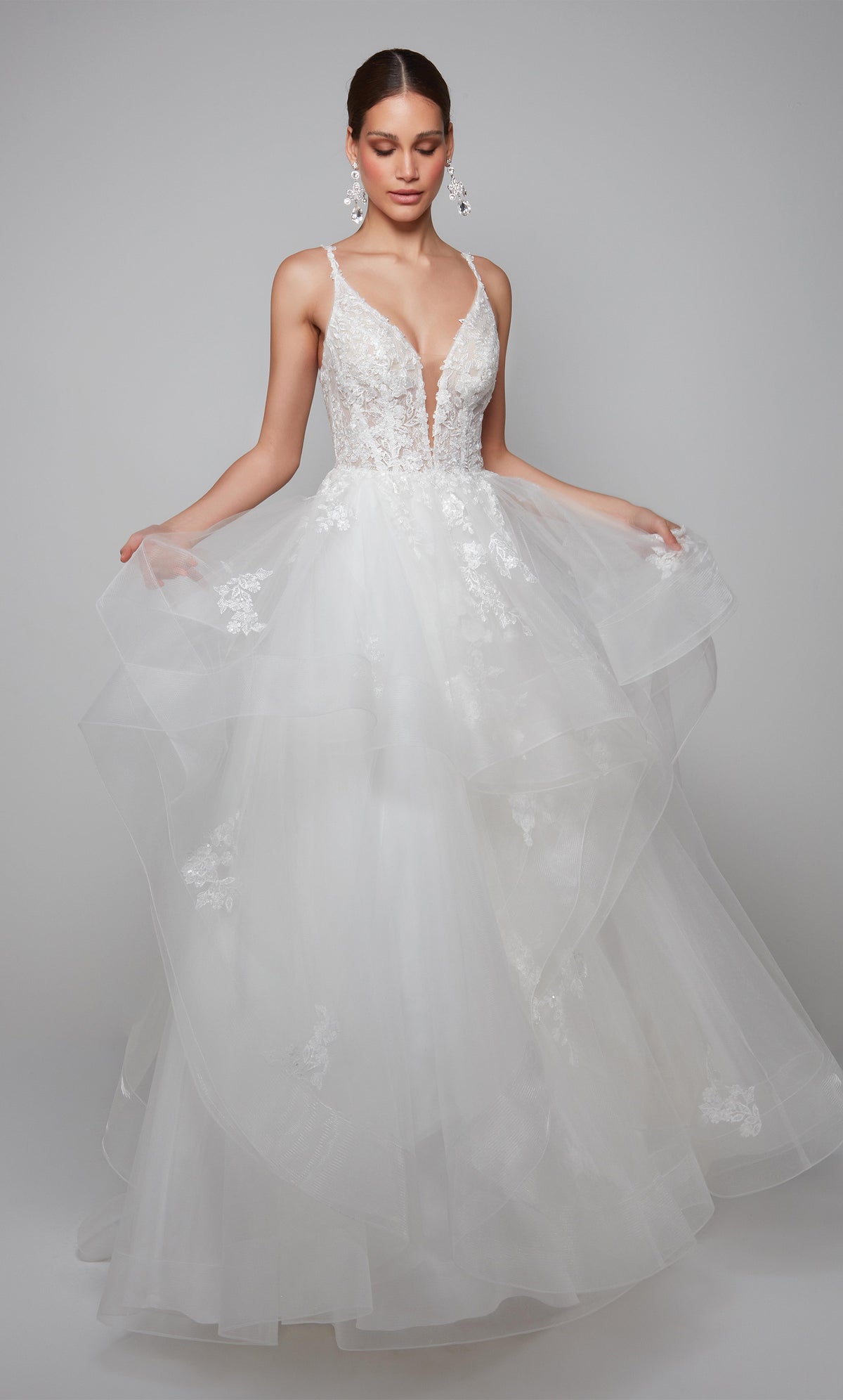Plunging floral lace applique wedding dress with a sheer bodice and layered skirt in ivory.
