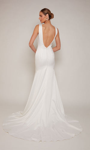 A white, satin wedding gown spotlighting a V-shaped open back and train adorned with satin covered buttons.