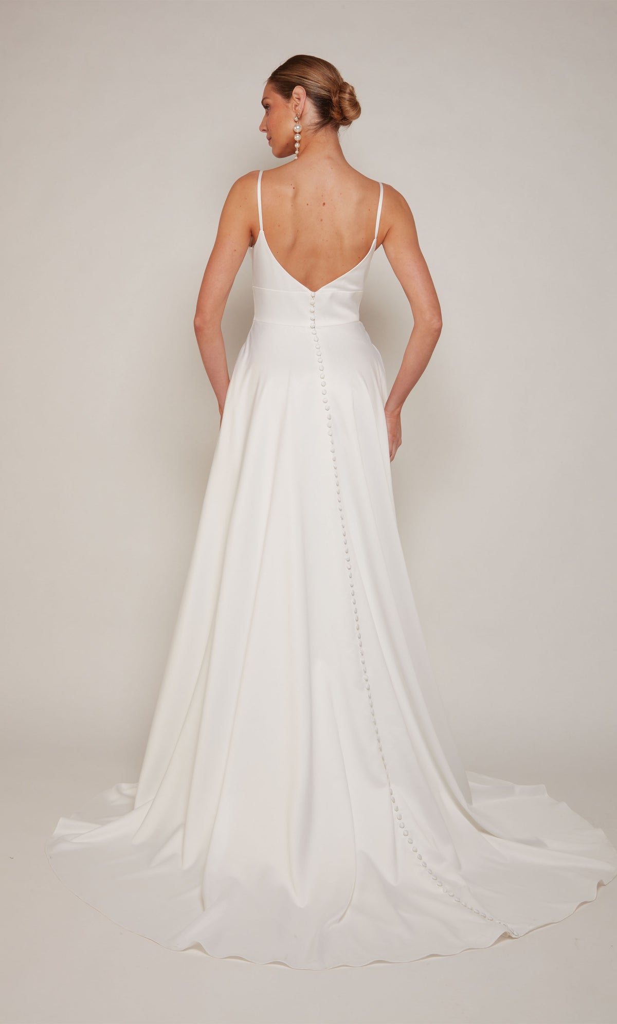 A simple, satin wedding dress with a low V-back style and satin covered buttons cascading down the back to the end of the train.