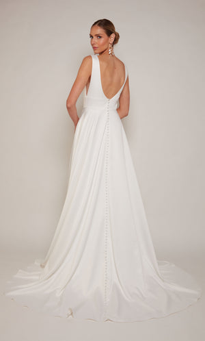 Simple satin A-line wedding dress in diamond white with a plunging neckline, open back, and satin covered buttons on the elegant train.