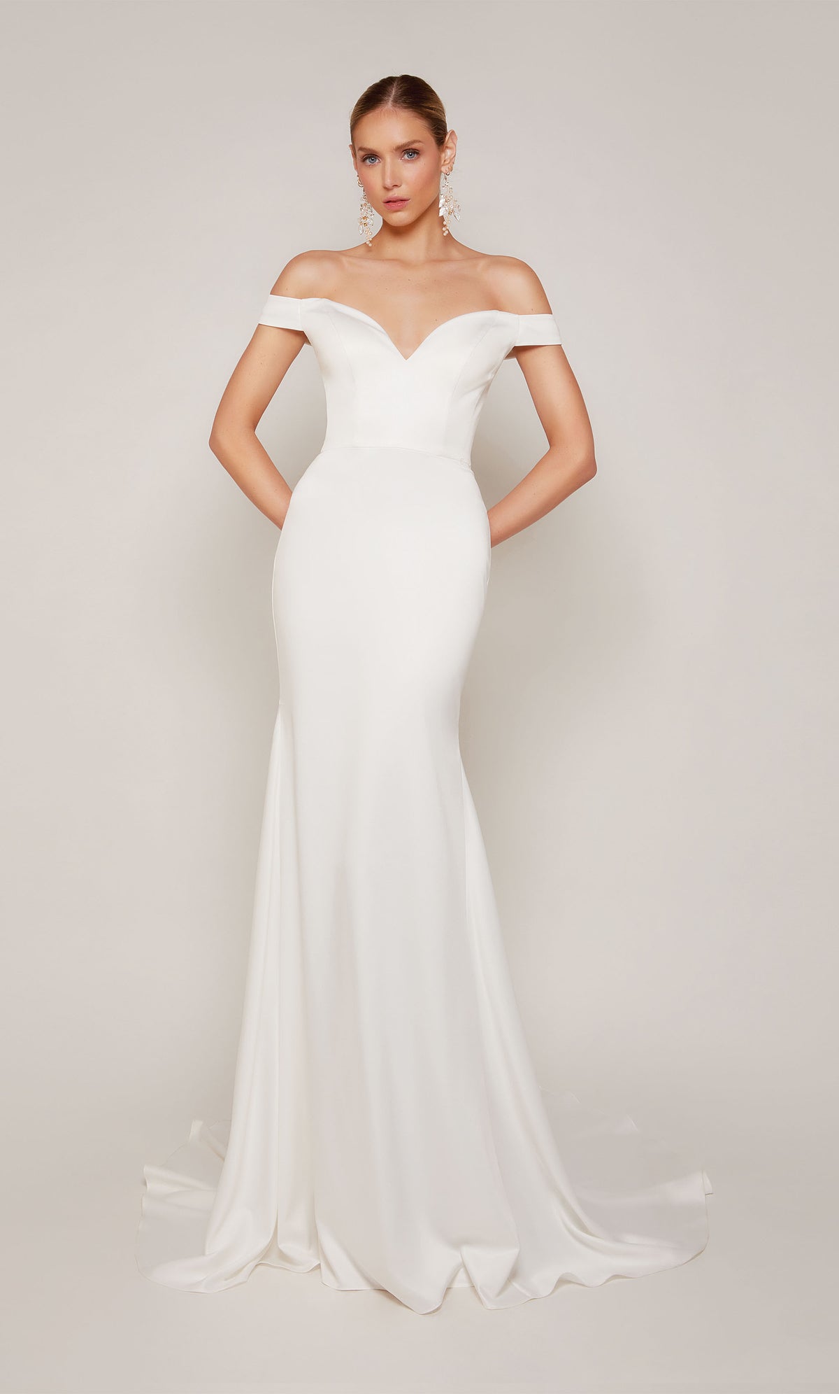 A sophisticated, off-the-shoulder satin wedding dress with a detachable train and satin-covered buttons 