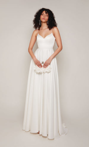 A classic, satin A-line wedding dress featuring a semi-sweetheart neckline and pearl embellishments on the straps, at the waistline, and on the illusion back. The dress also has an elegant train with satin-covered buttons down the back.