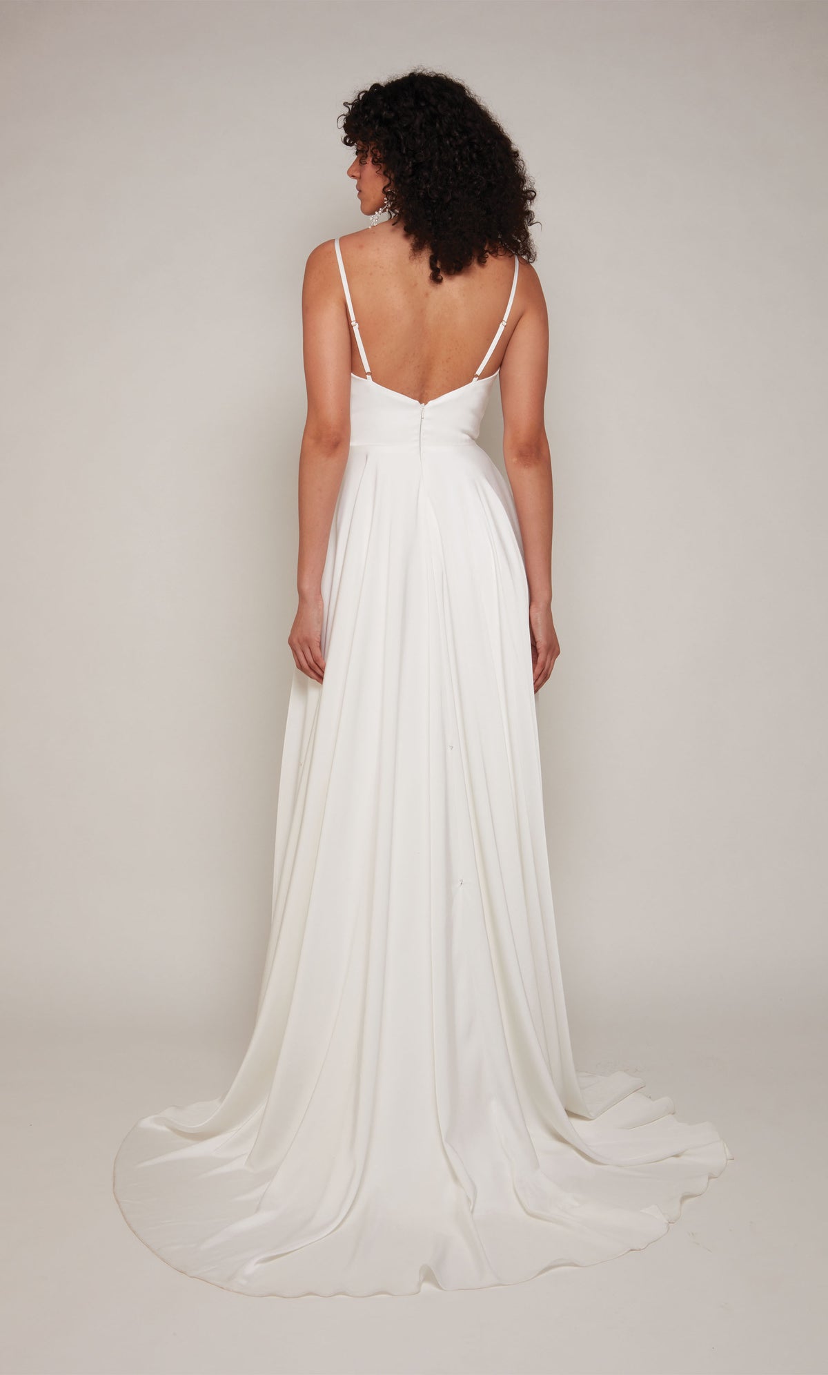 A simple wedding dress in white satin with an A-line skirt, an open back, adjustable spaghetti straps, and a train.